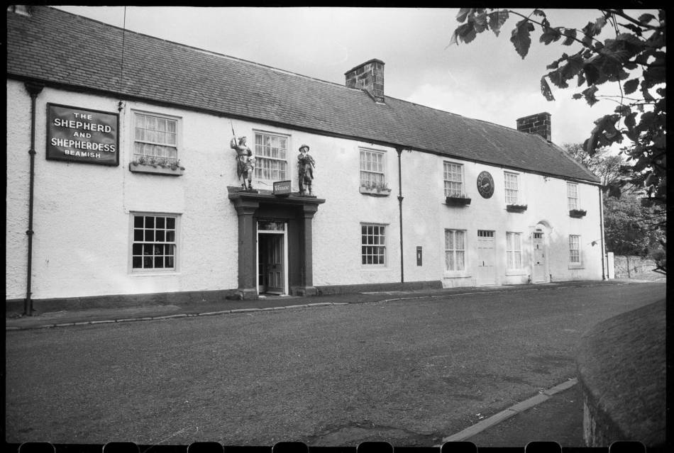 A black and white archive image of a public house, over the entrance are two life-size statues.