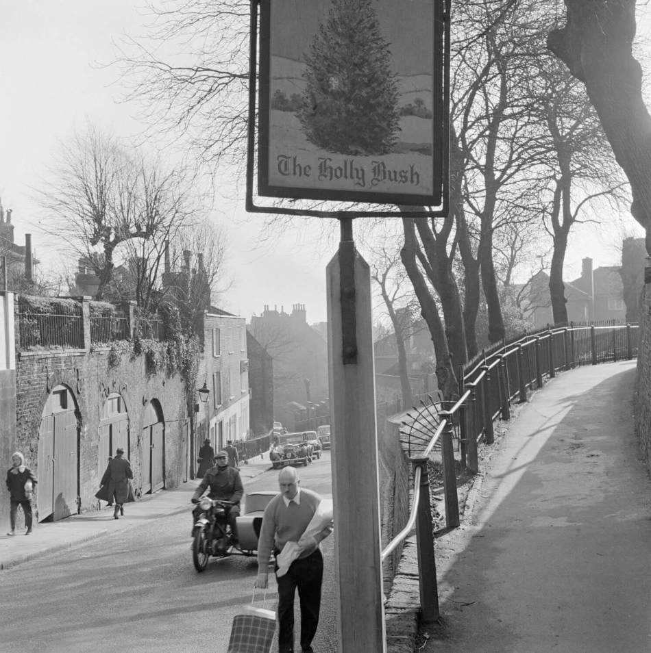 Black and white street scene showing hanging sign for The Holly Bush.