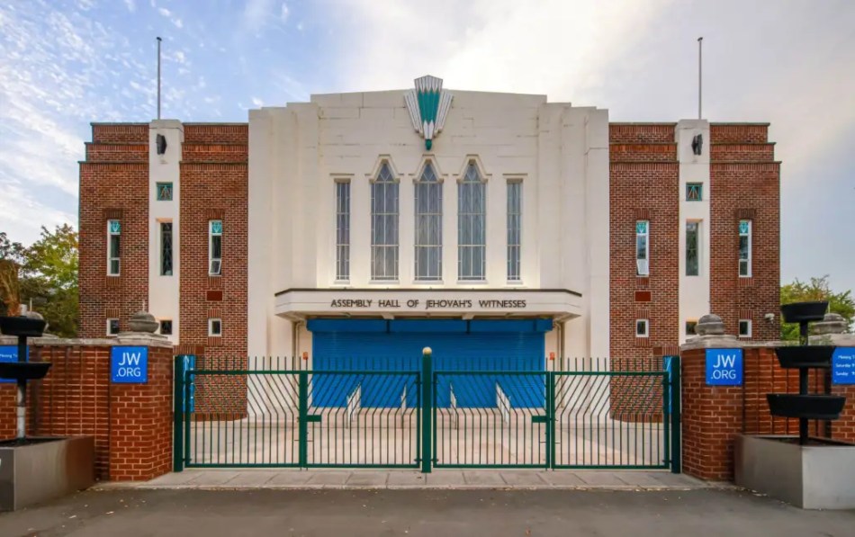 The exterior of a converted historic cinema built of brick with a rendered entrance bay.