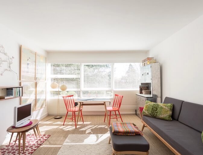 Sunlit living room with modern furniture casting shadows across coir flooring and rugs.
