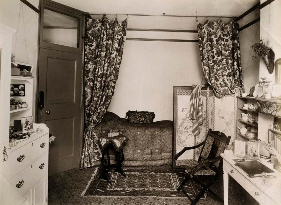 A Victorian-era room featuring a screened bed alcove. 