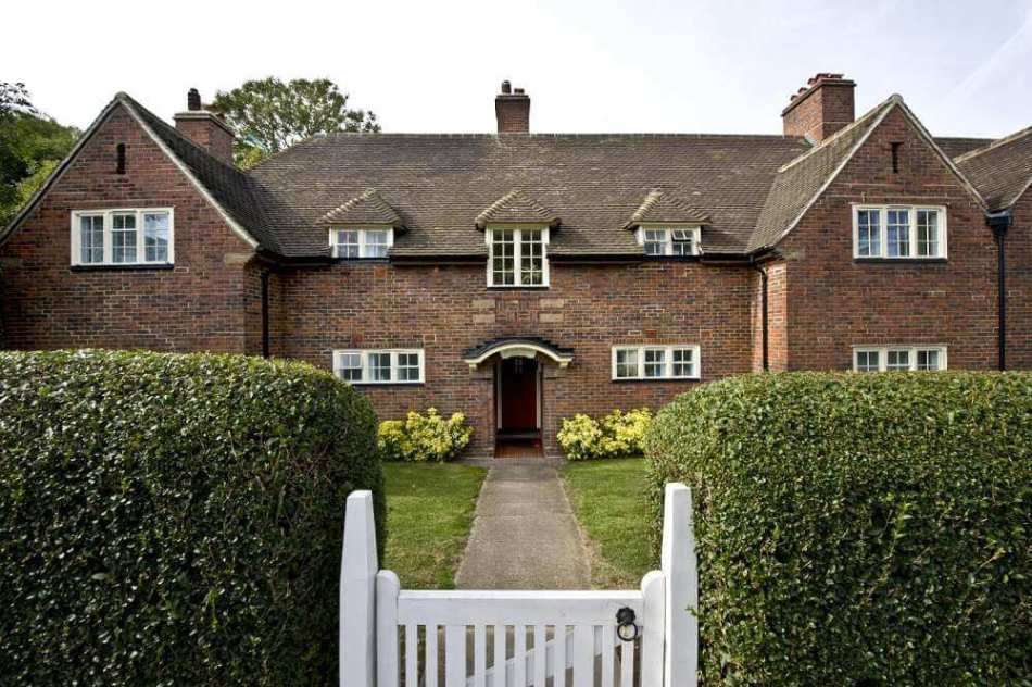 A colour photograph of a brick building with two wings, viewed across a lawn.