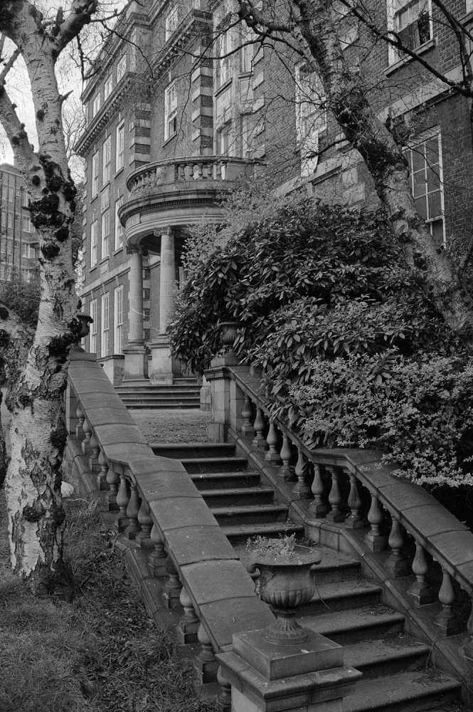 Black and white archive image of a brick building with stone details, steps lead up to the entrance.