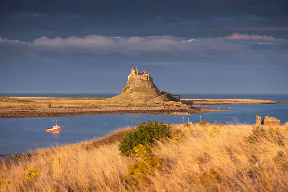 A colour photograph showing a stone castle built in a raised position on an Island.