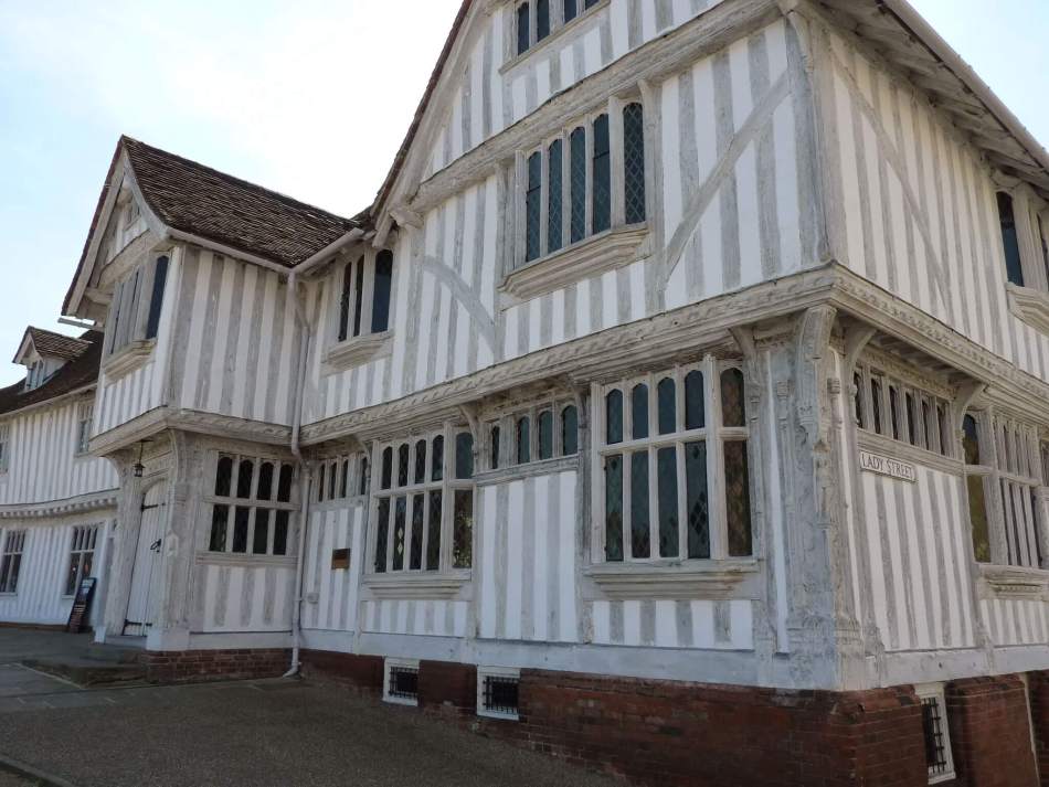 A colour photograph of a medieval timber framed-building with jettied upper storey and gabled roofs.