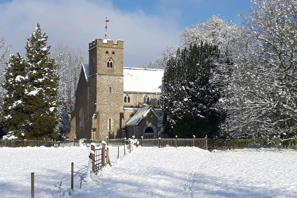 A colour photograph of a stone church taken with snow on the ground.
