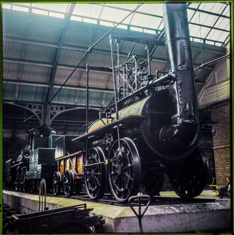 A photograph of the front section of a steam train on display in a large station building.