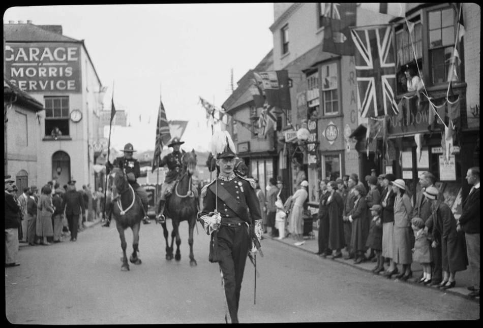 A man in military uniform, possibly a Lord Lieutenant, and Canadian Mounted Police passing crowds on the High Street.