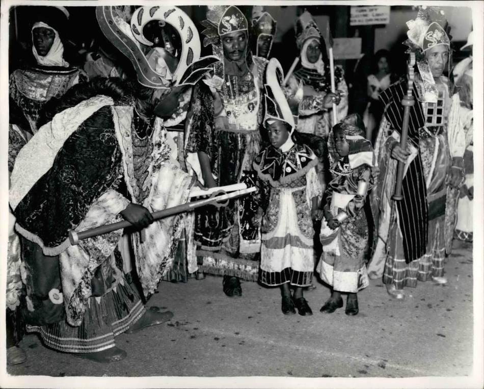 A black and white photograph showing dancers and children dressed in costume. 