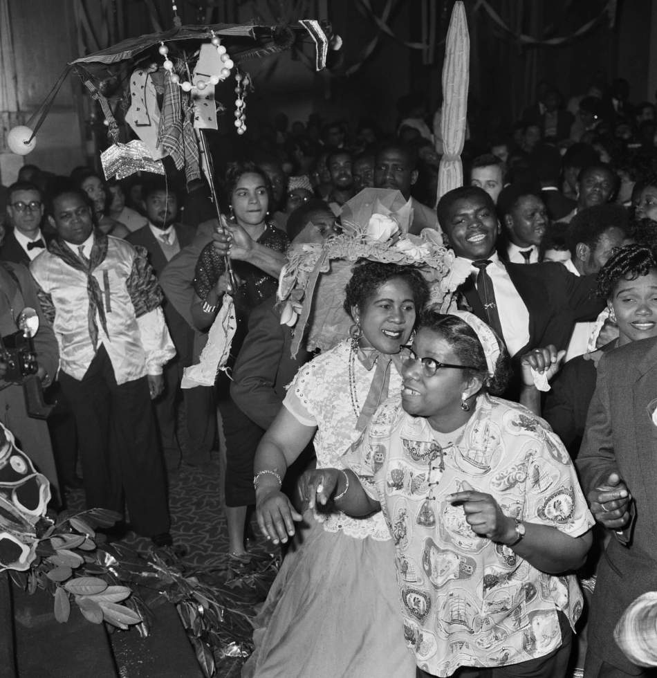 A black and white photograph showing people dancing in a crowded space. 