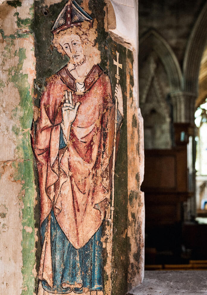 A photograph of a deteriorating wall painting of a clerical figure.