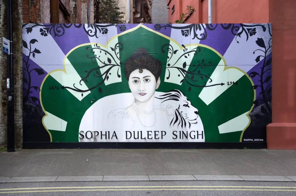 A photograph of the side of a wall covered in colourful street art featuring an illustration of Sophia Duleep Singh and the outline of a lion.