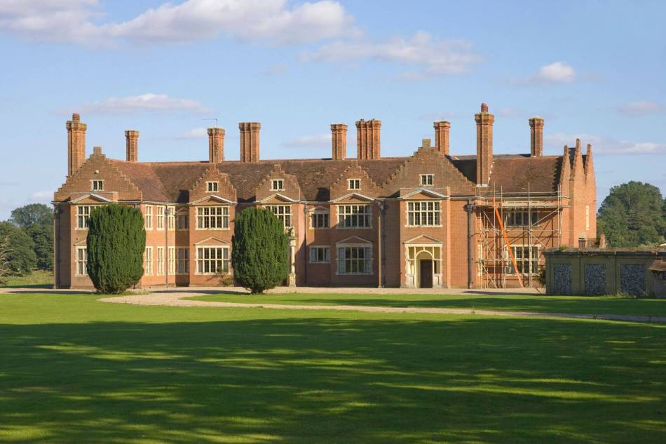 A photograph of the exterior of a large, stately home in a Jacobean-style, with several tall chimney stacks.