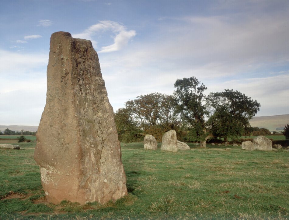 A photograph of a prehistoric stone circle with a standing stone in the foreground.