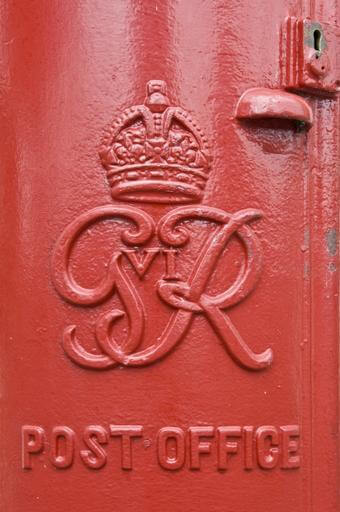 A photograph of a close-up of an insignia on a post box. The lettering features 'GR VI'.