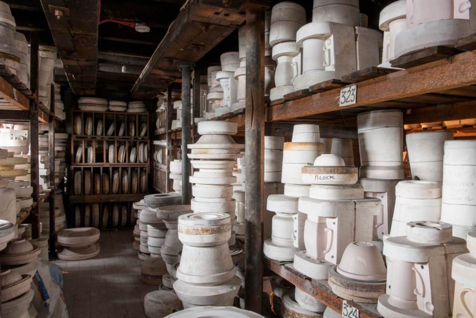 A photograph of the interior of a pottery store, with shelves stacked with ceramic pots and moulds.