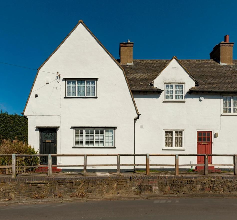 A photograph of the exterior of the end of a terrace of houses beside a road.