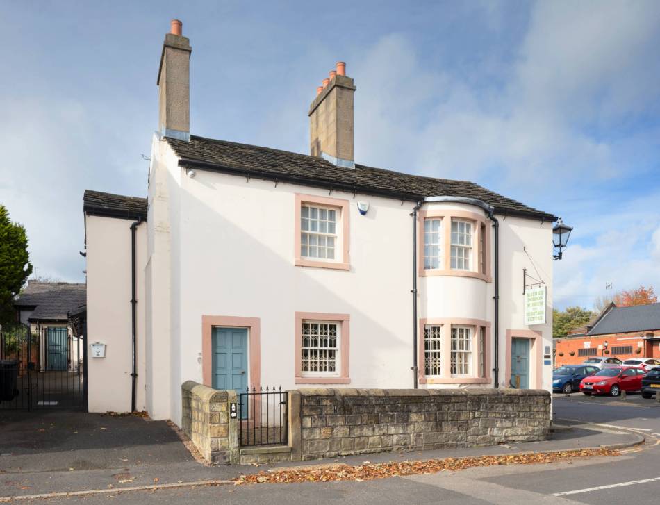 A photograph of a two storey white semi detached houses with blue doors.