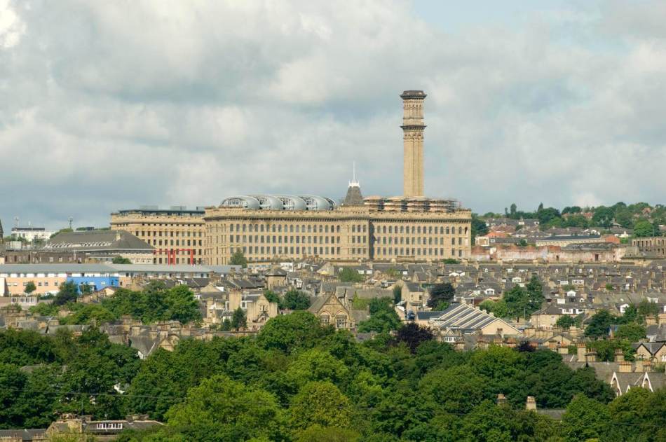 A photograph of a cityscape with a large mill building in the background with a tall tower.