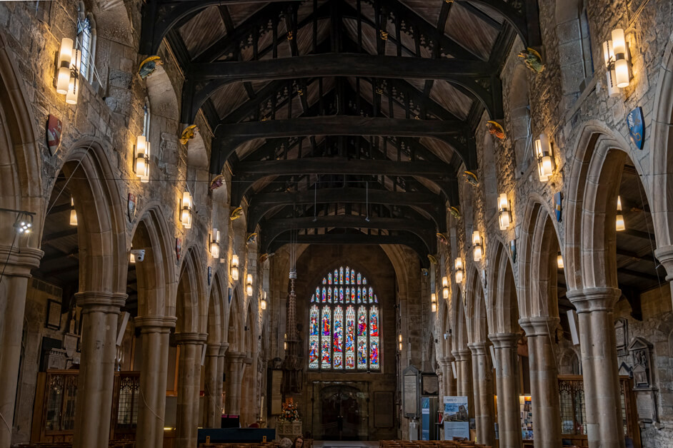 A photograph of the interior of the nave of a cathedral with a brightly coloured stained glass window at the end.