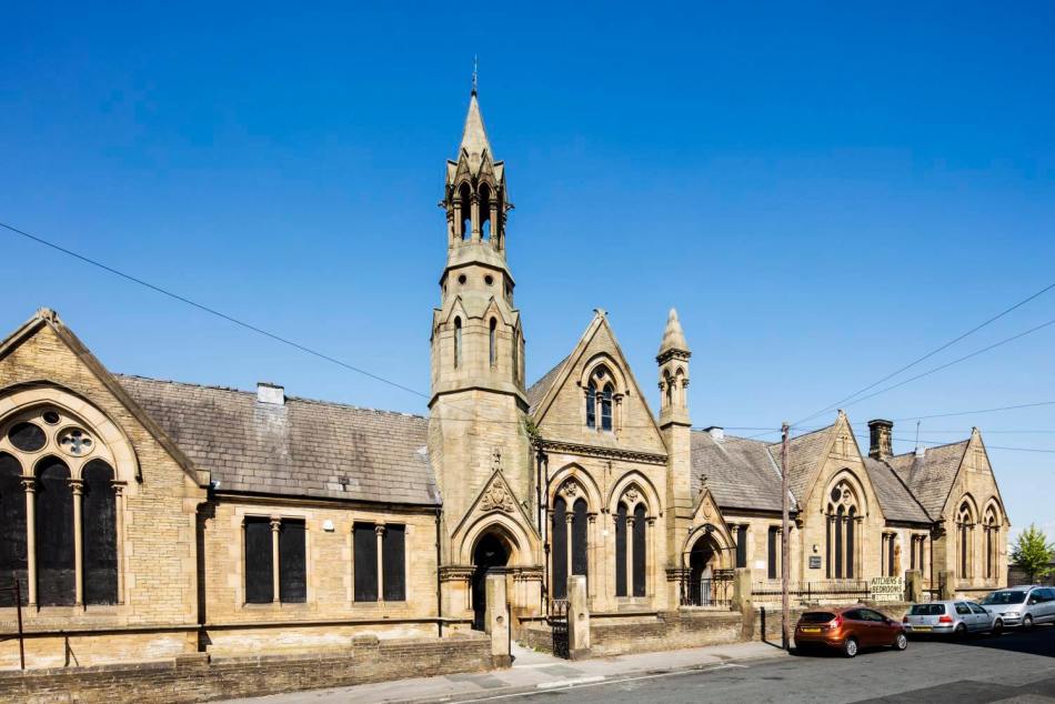 A photograph of the exterior of a single-storey Gothic Revival-style school beside a road.