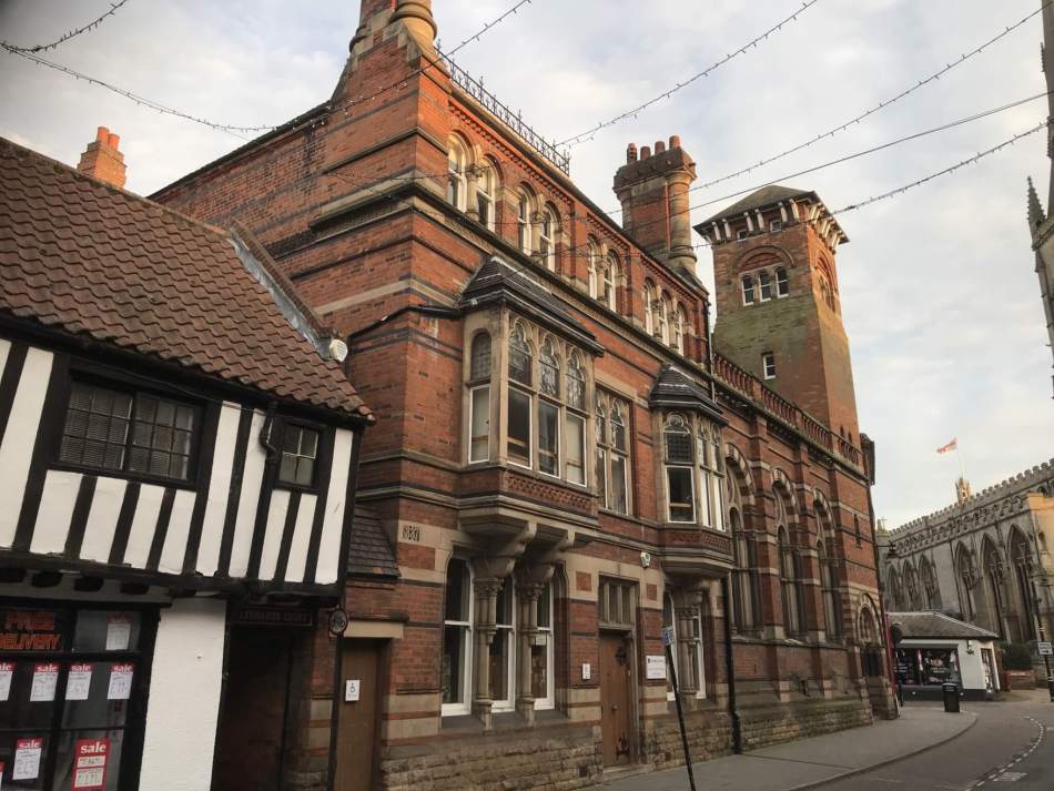 A colour photograph of a large, ornate, red brick building. 