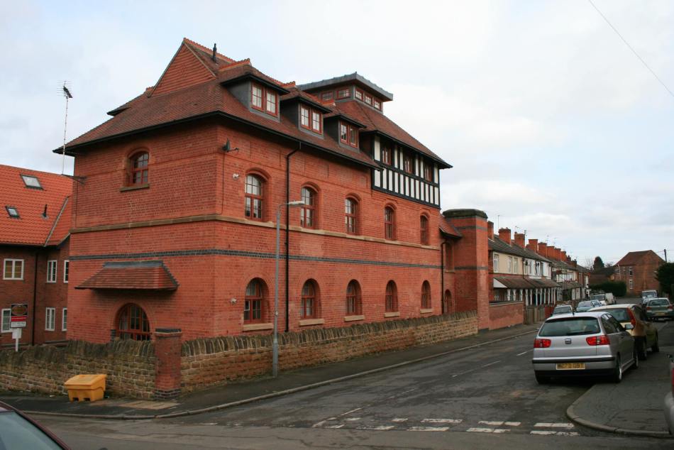 A colour photograph of a large red brick building with several storeys. 