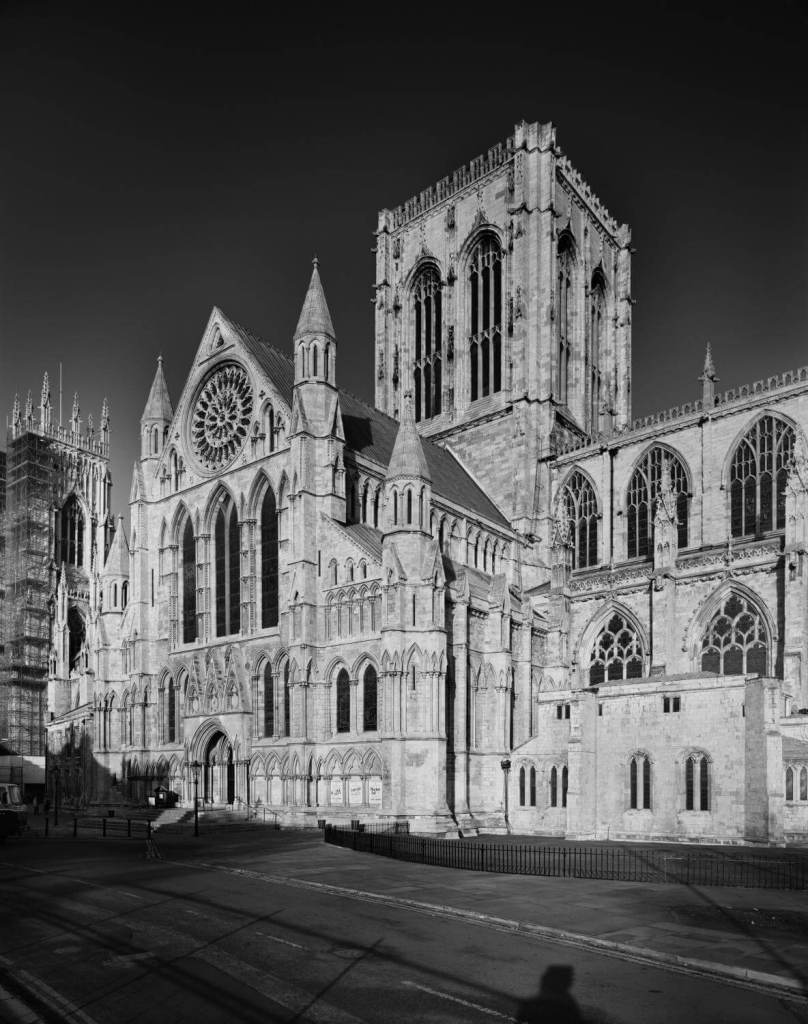 A black and white photograph of the exterior of a grand medieval minster. 