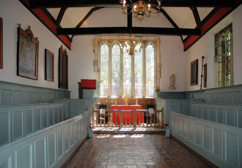 A photograph of the interior of a medieval building with a blue panelled seating area.  