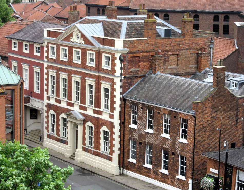 A photograph of a street with a Georgian 3 storey red brick house.