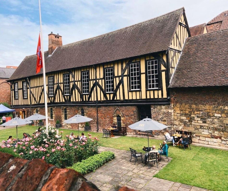 A photograph of a two storey yellow timbre framed building with a brick bottom storey. 