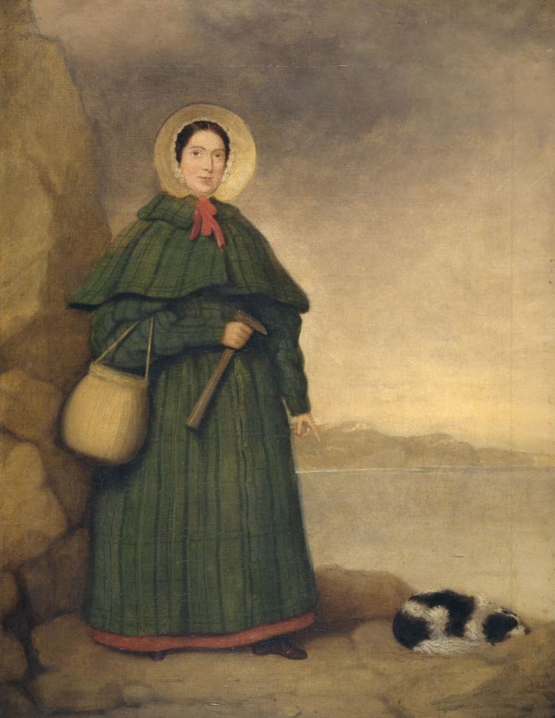 A photograph of a portrait of Mary Anning stood next to a dog.