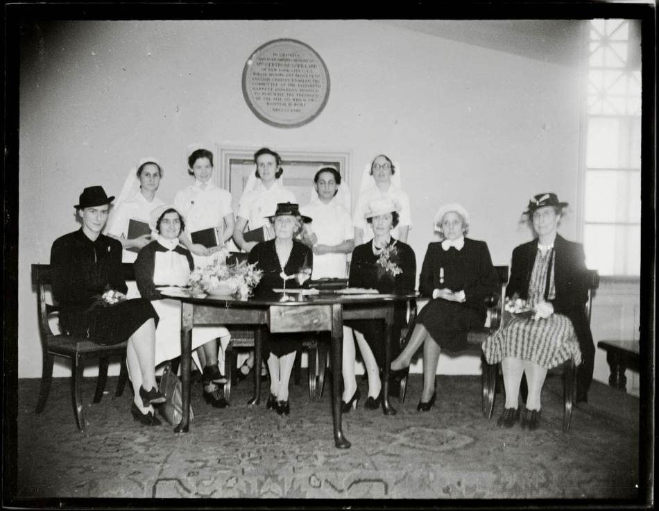 A black and white photograph of women seated around a table. 