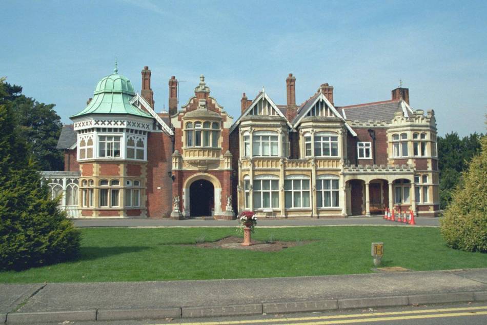 The exterior of a grand house with grass in the foreground. 