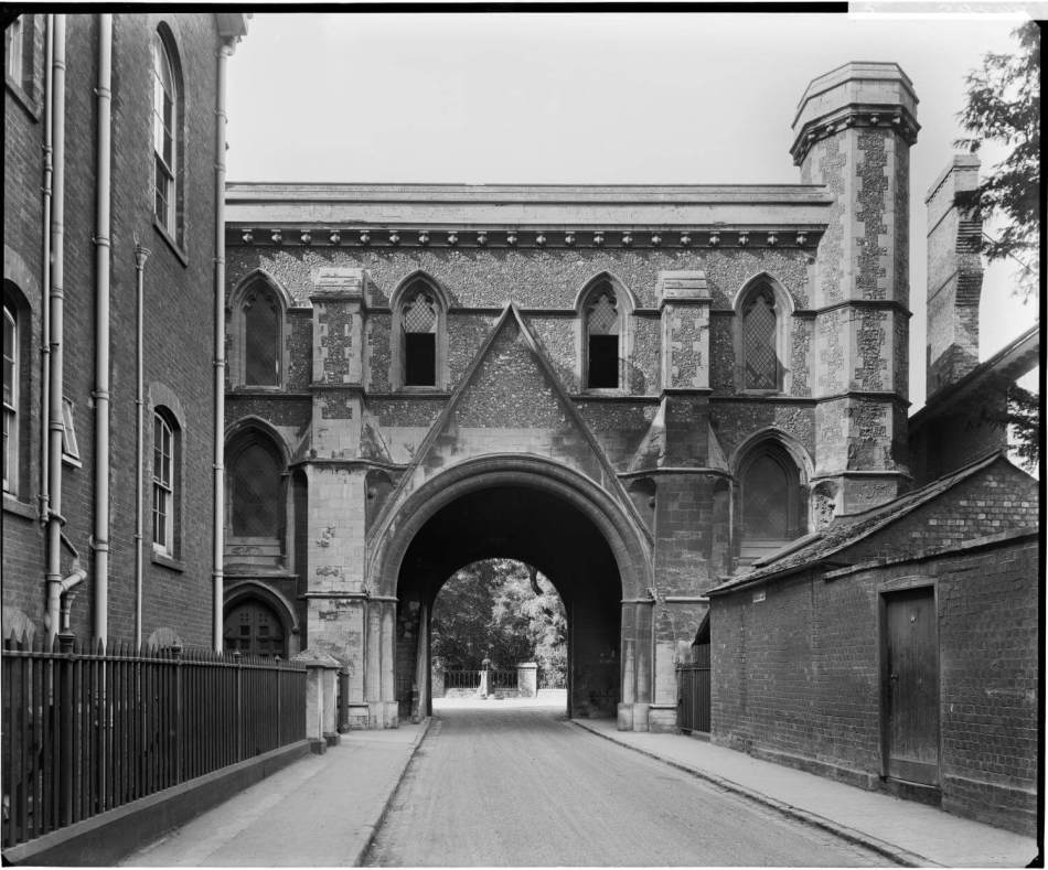 A black and white photograph of a 2-storey gateway arch over a small road.