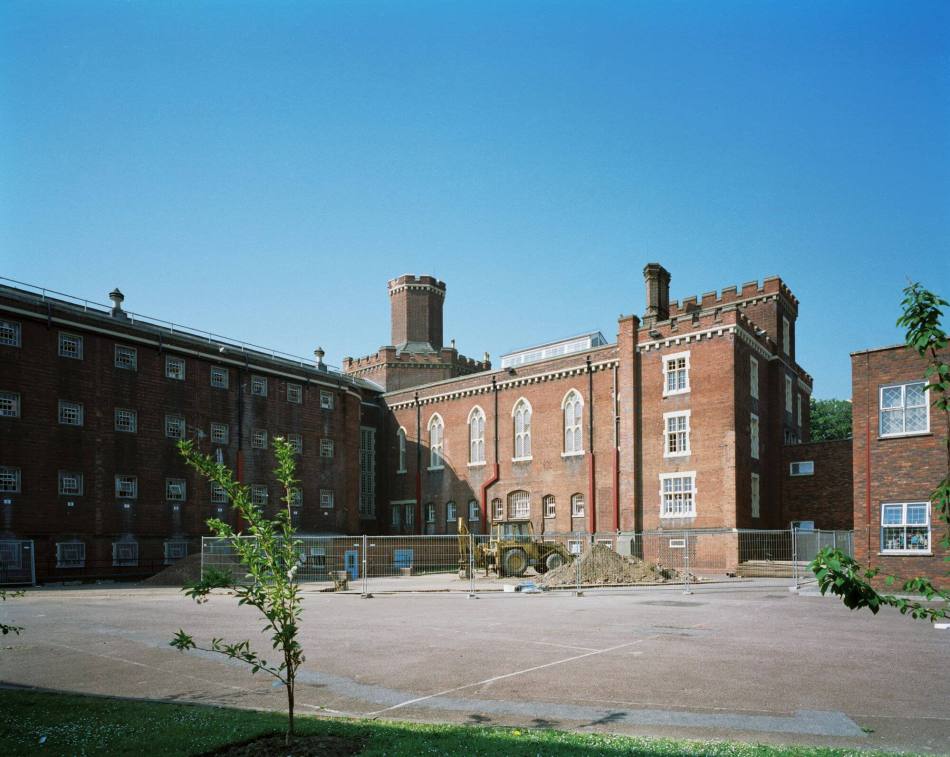 A photograph of the exterior of a wing of a red brick jail building.