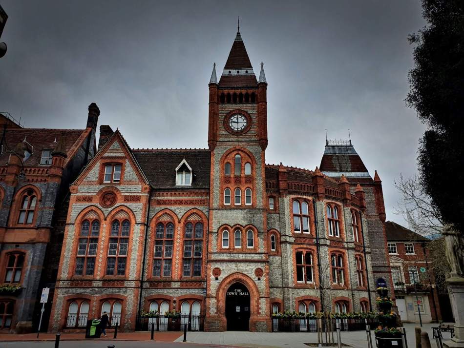 A photograph of the exterior of a large town hall with a tall clock tower at the centre.