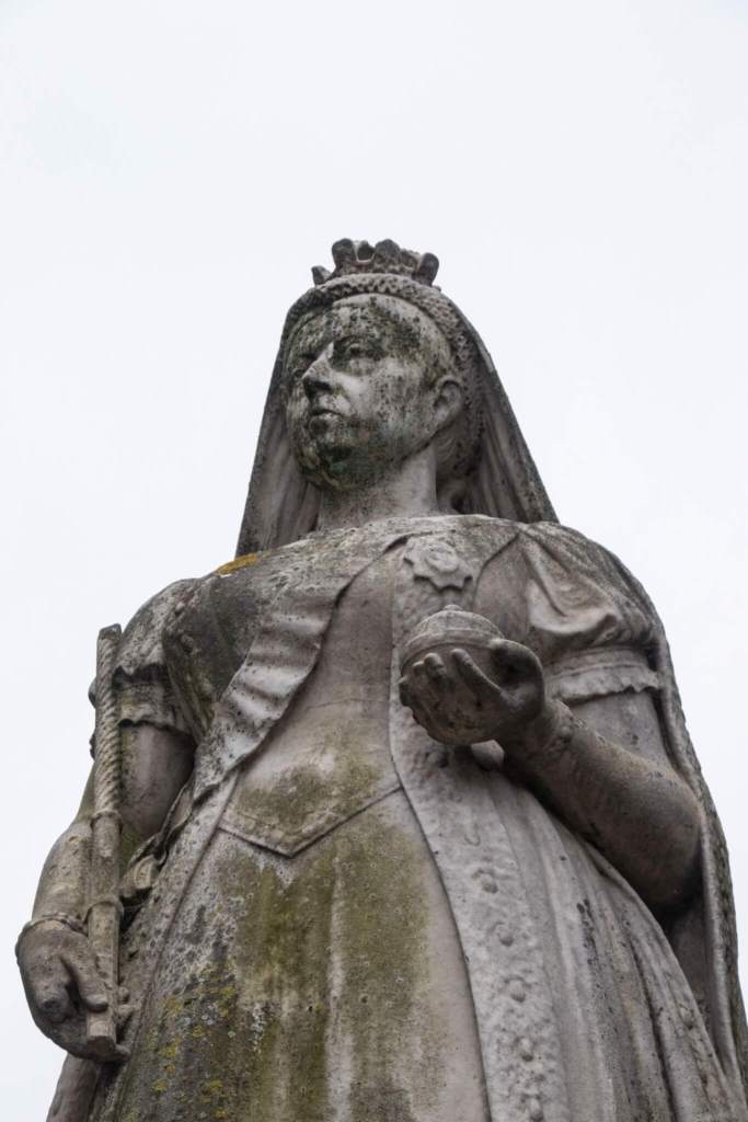 A photograph of a close-up of a statue of Queen Victoria holding an orb and sceptre. 