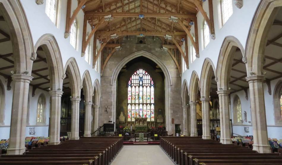 A photograph of the interior of a Church with a timber-framed beam ceiling.