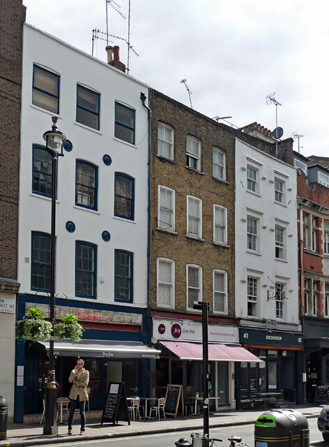 A photograph of a terrace of 4-storey buildings with shops and cafes on the ground floor.