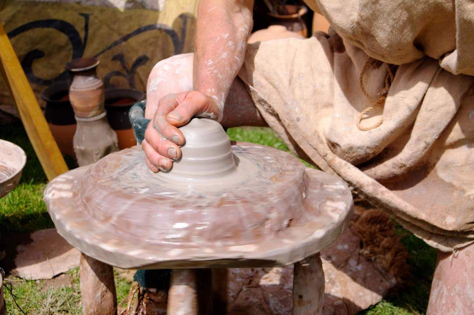 A reenactor using a roman potter's wheel.