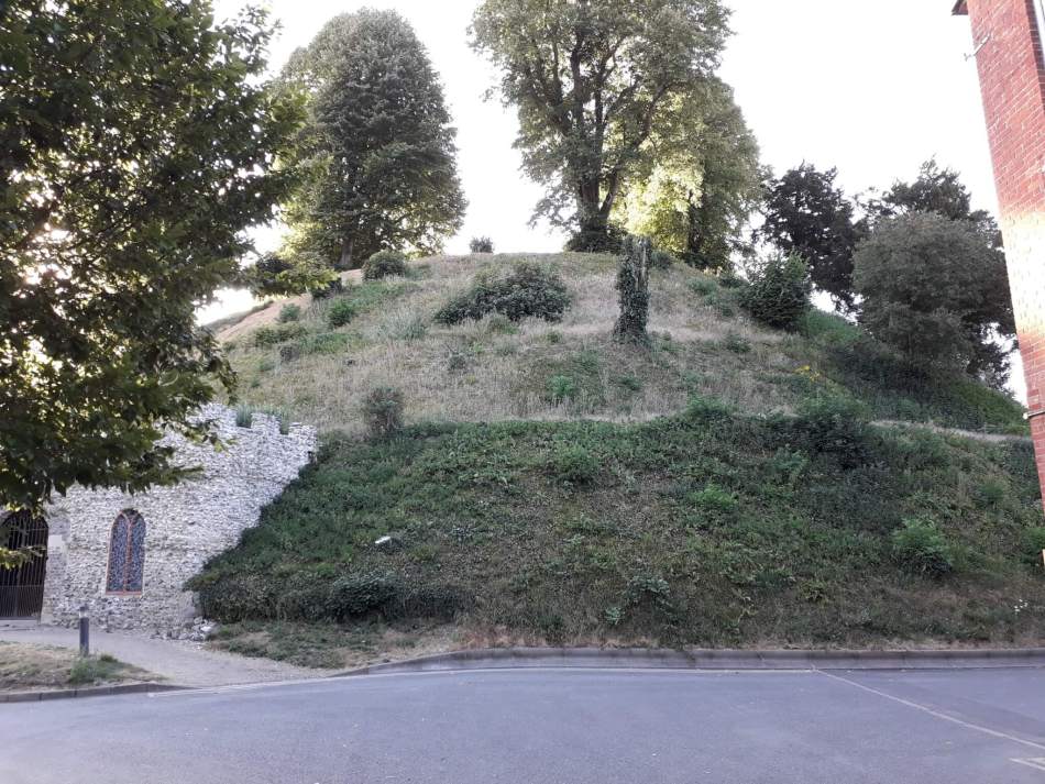 A photograph of a prehistoric mound with later stone walls.