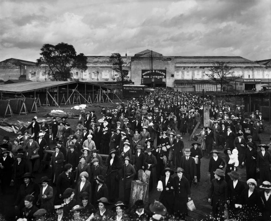 A black and white photograph of a large group of workers leaving the entrance of a factory.