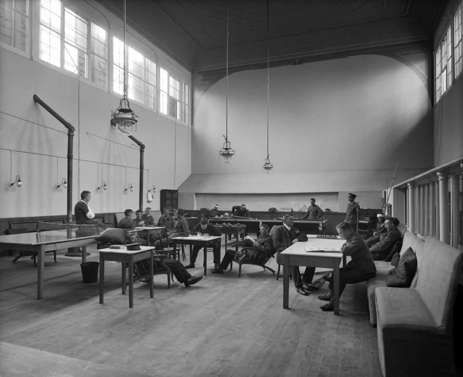 A black and white photograph of First World War service members sitting at tables in a recreation room.