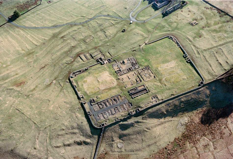 An aerial view of the ruins of a roman fort and associated earthworks.