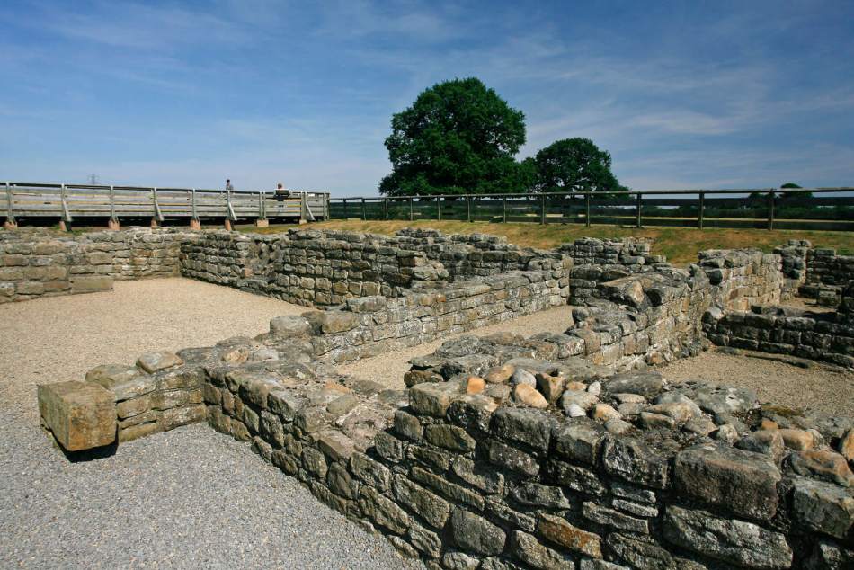 A photograph of the excavated foundations of a Roman Fort, with visitors in the background.