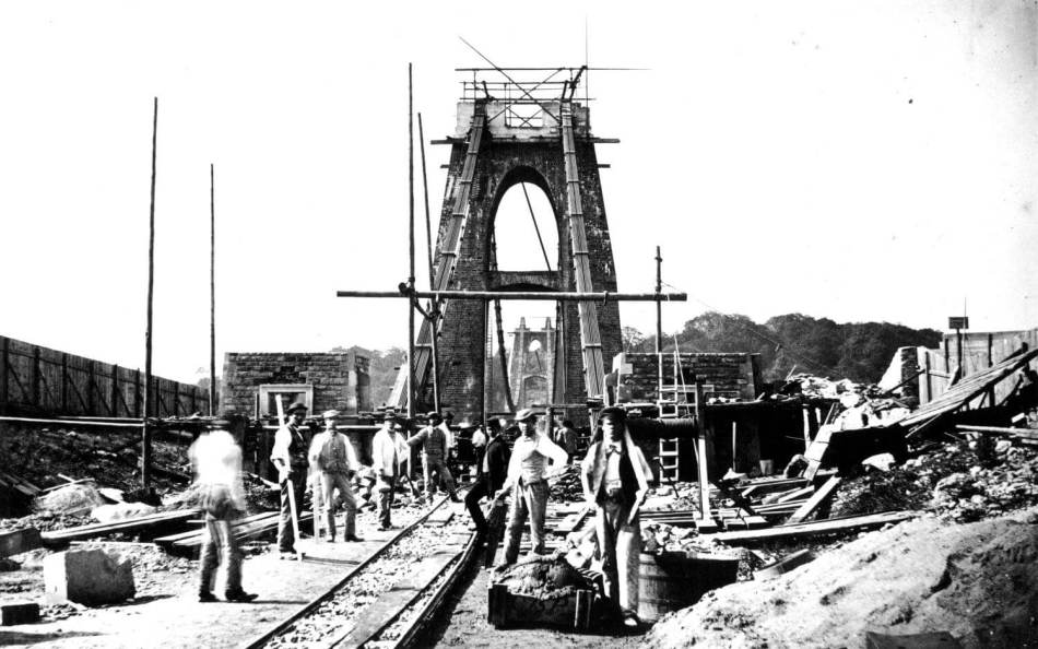 A black and white photograph of people building a bridge