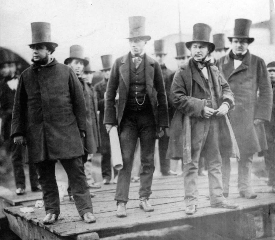 A black and white photograph of Isambard Kingdom Brunel and other engineers standing on the side of a dock.