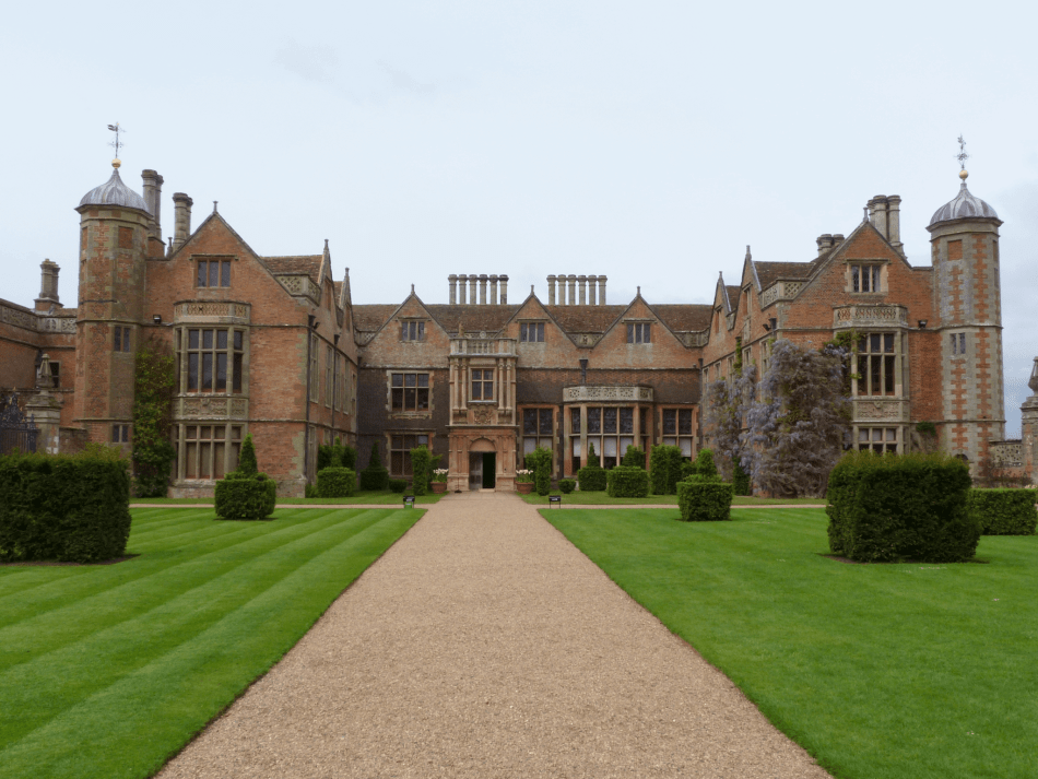 A photograph of a red brick Elizabethan manor house.