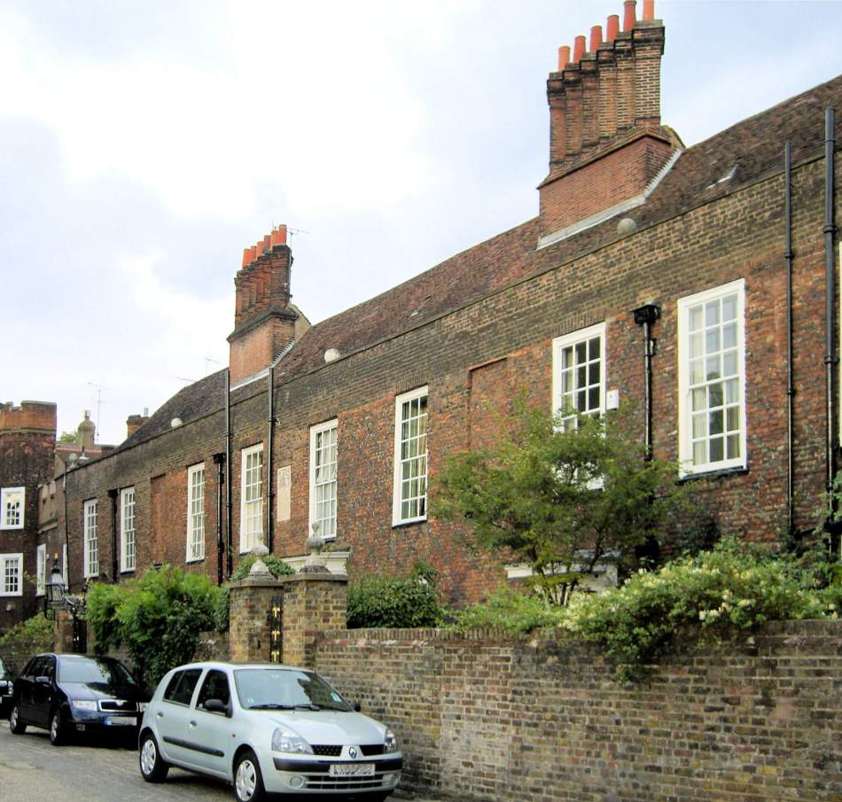 A photograph of a row of 18th century red brick terraces with large chimneys.